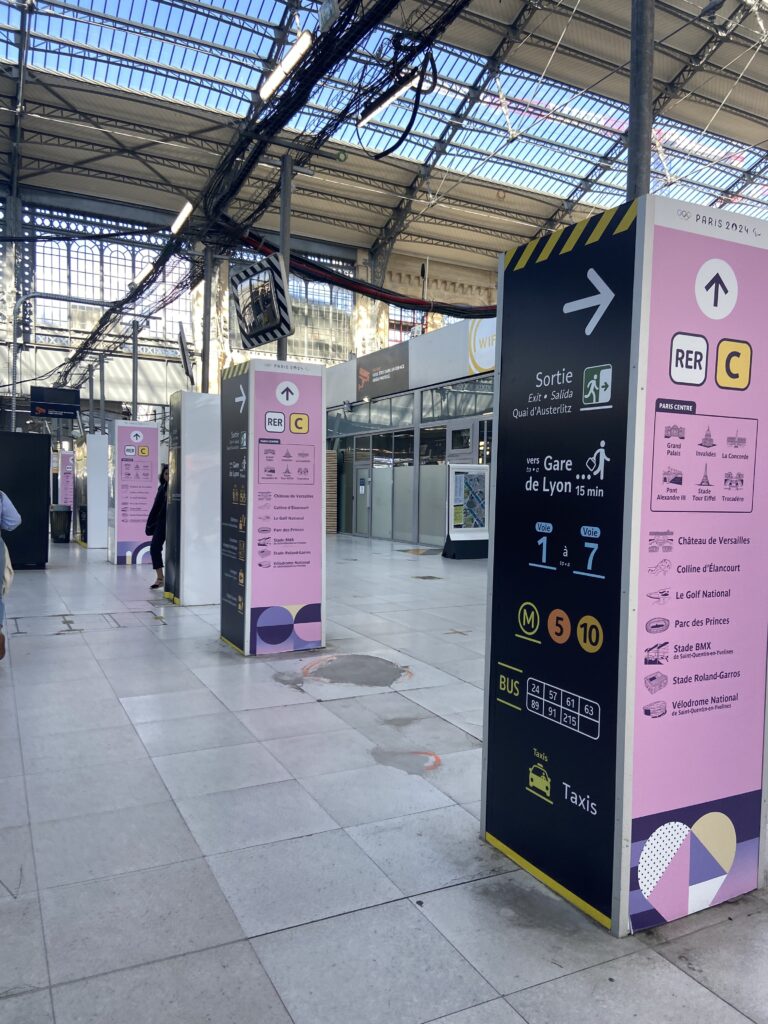 Image of pink wayfinding signs at a train station in Paris